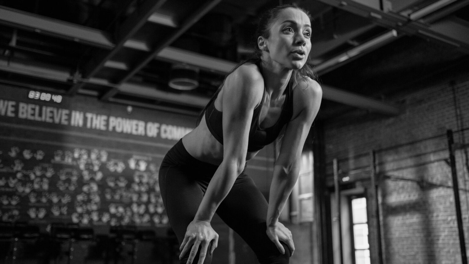 A female athlete resting between sets in a gym, emphasizing the importance of recovery and fueling with the right macronutrient strategy, including carb cycling.