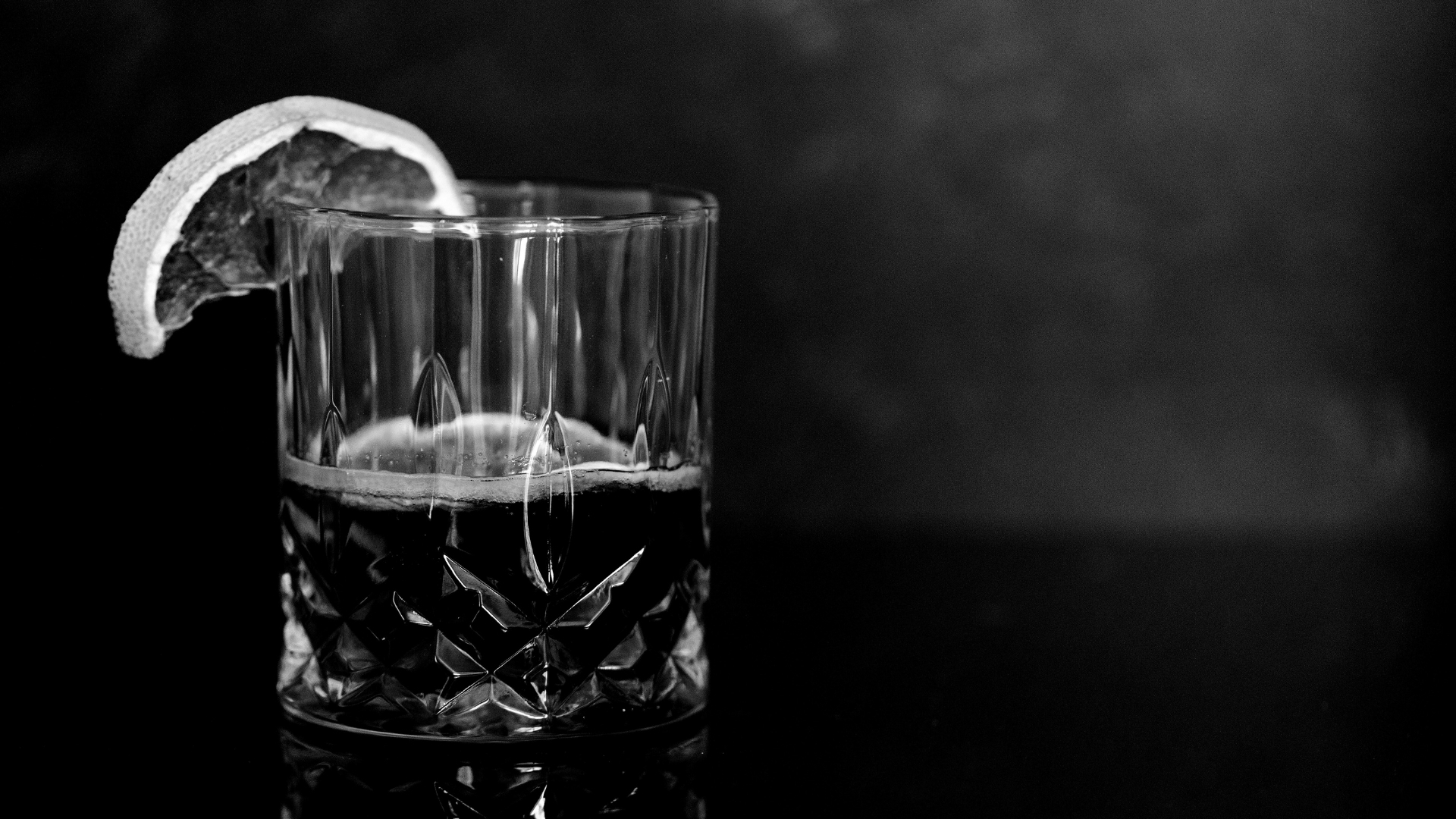 A glass of alcohol with a citrus garnish, representing the hidden calories and metabolic effects of drinking on fitness and weight training.