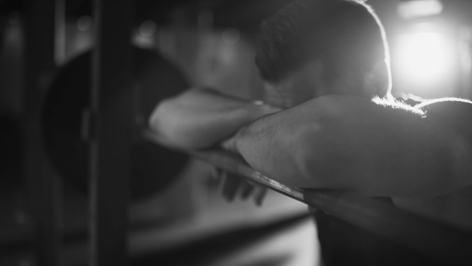 Exhausted athlete resting on a barbell in the gym, illustrating how alcohol impacts muscle recovery, fatigue, and performance.