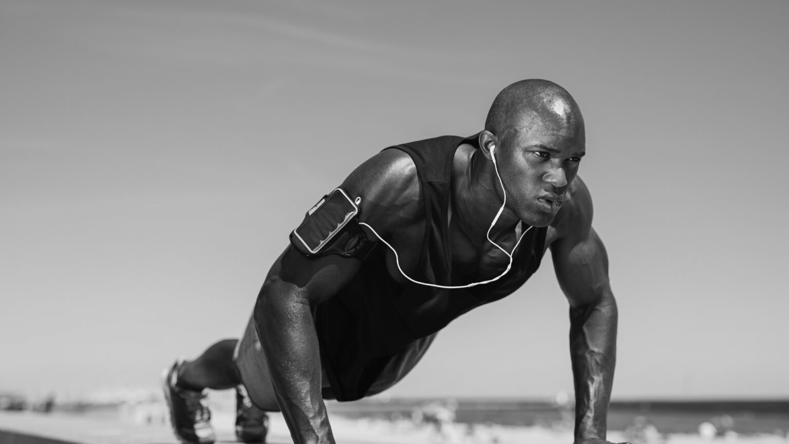 Determined runner holding a plank position, showcasing upper body and core strength training for endurance athletes.