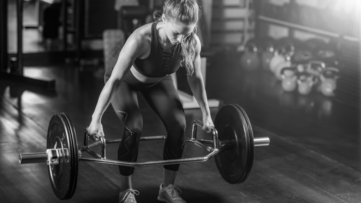 Female fitness enthusiast performing a trap bar deadlift, strengthening the posterior chain and improving athletic performance.