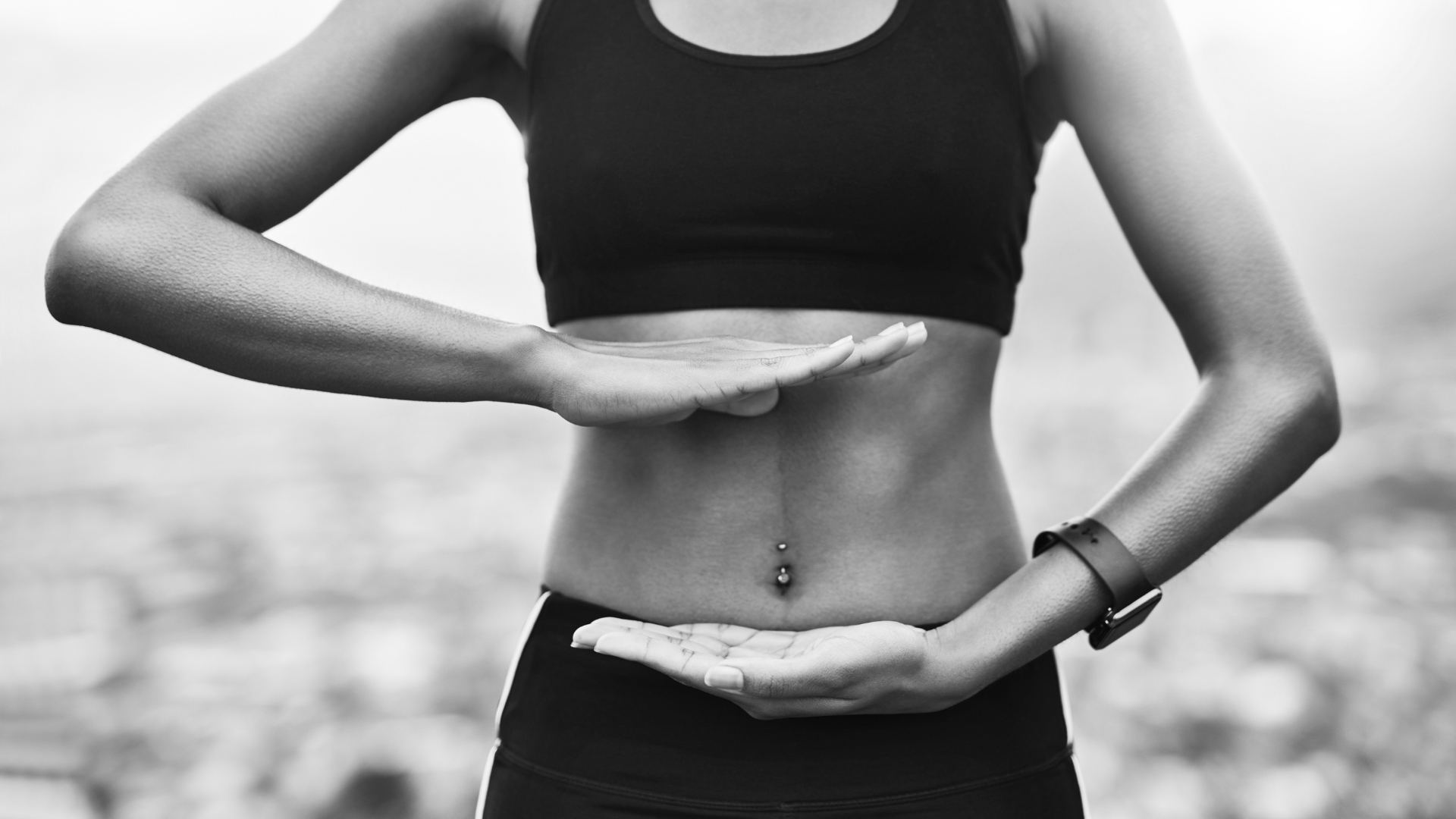 Fit woman holding her hands around her core, symbolizing strength and stability.