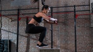 Dynamic box jump workout in a brick-wall gym, highlighting plyometric training for explosive power and agility.