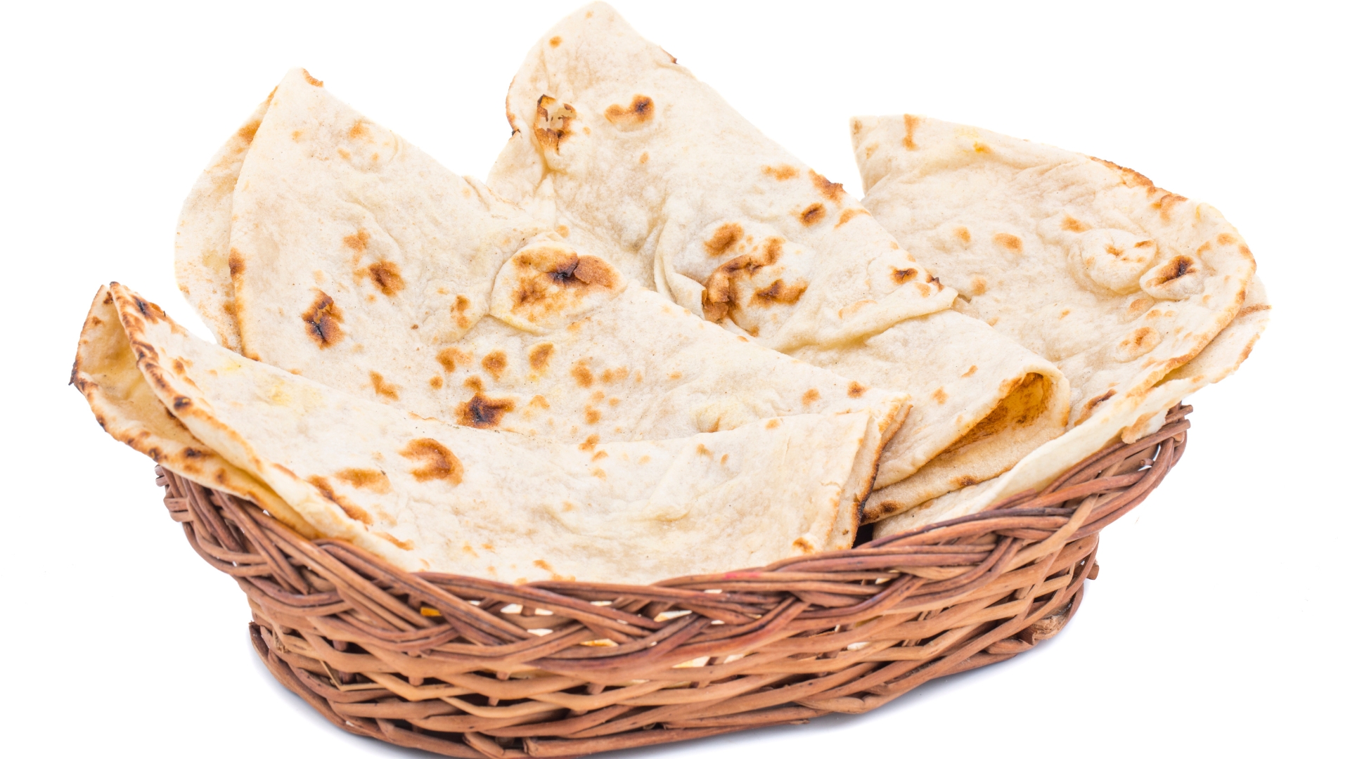 A basket filled with freshly made roti, lightly charred and folded, ready to be served.