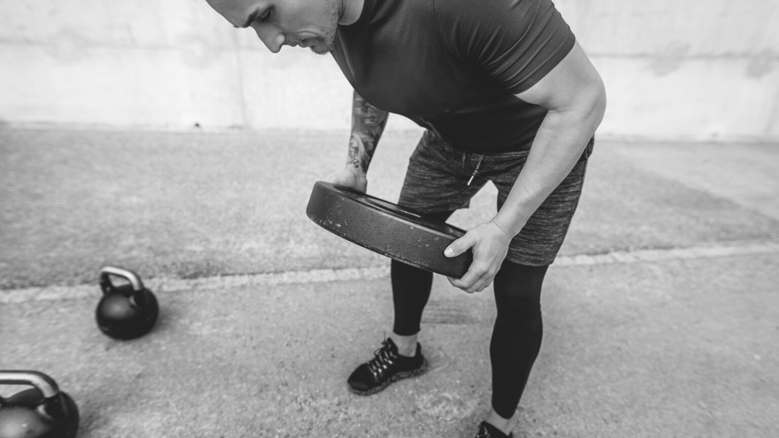 Male athlete executing a bent-over plate row, targeting back and posterior chain development for balance in a pull-focused workout.