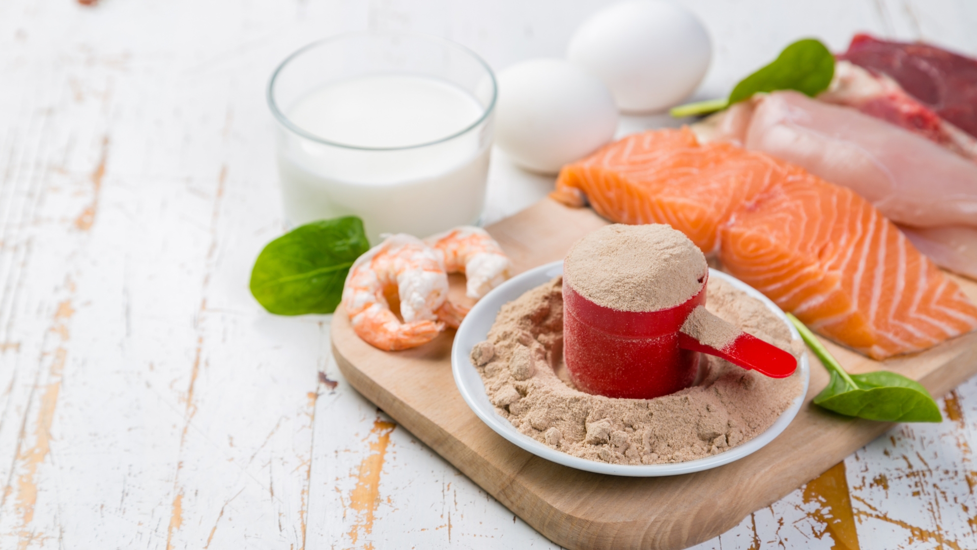 A balanced meal of whole food protein sources, including salmon, shrimp, eggs, and a scoop of protein powder, highlighting the difference between natural and supplement-based protein intake.