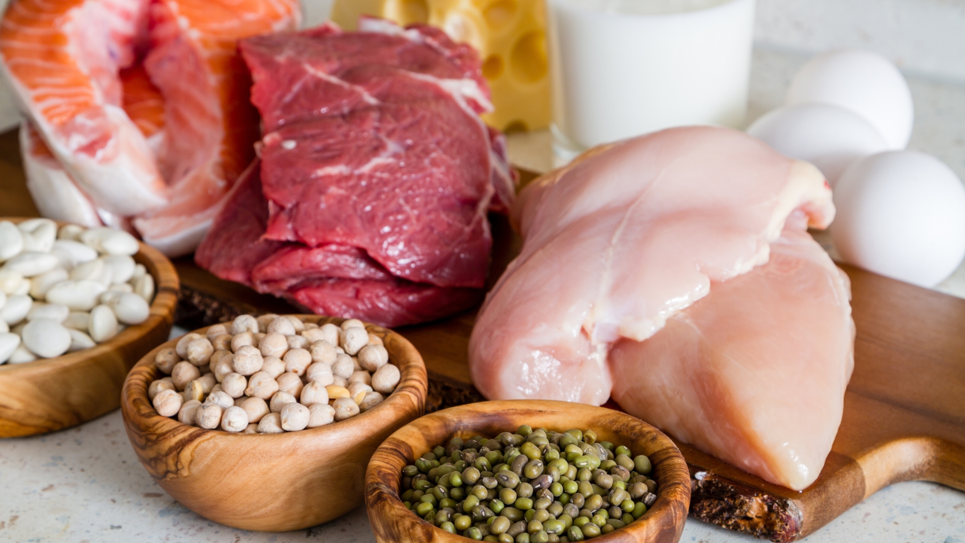 A variety of high-protein foods including red meat, fish, chicken, eggs, and legumes, showcasing natural sources of creatine.