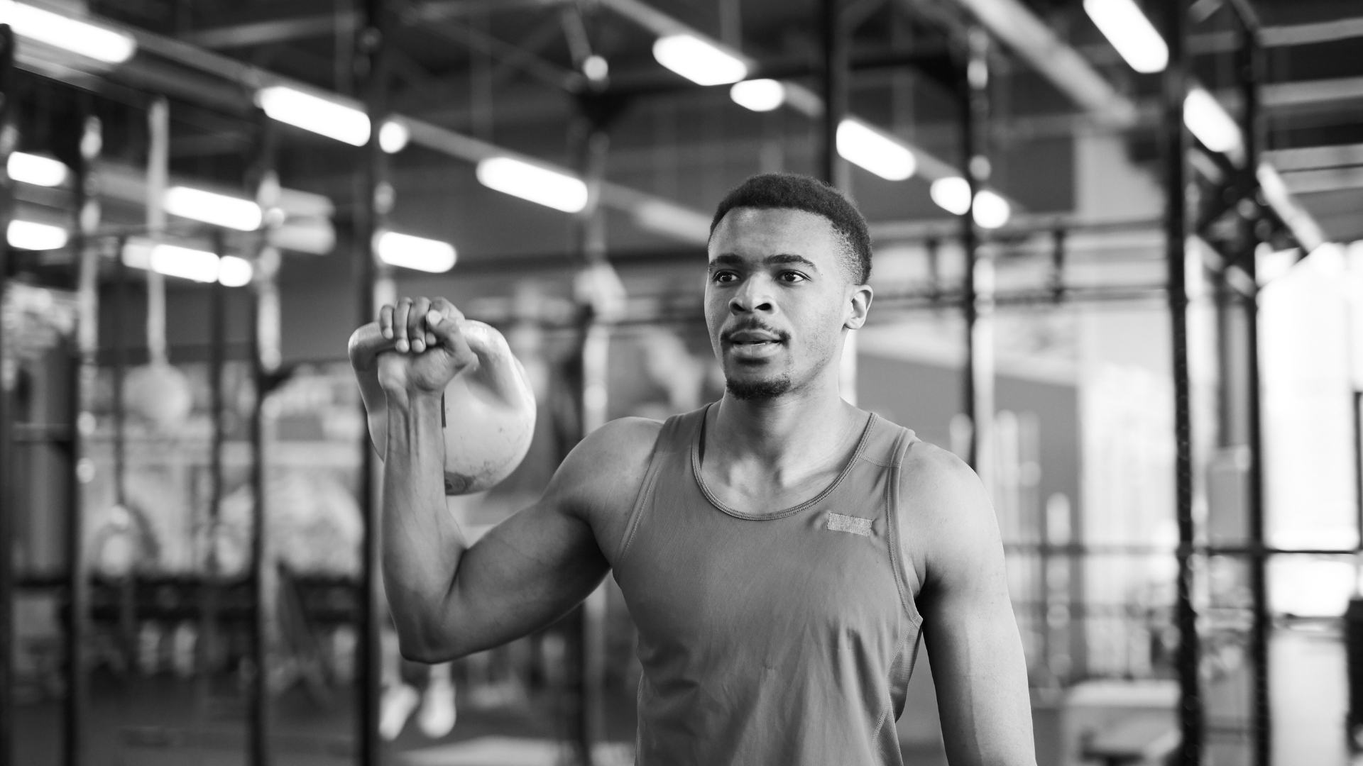 A focused male athlete performing a kettlebell clean inside a gym, demonstrating strength and precision in kettlebell training.