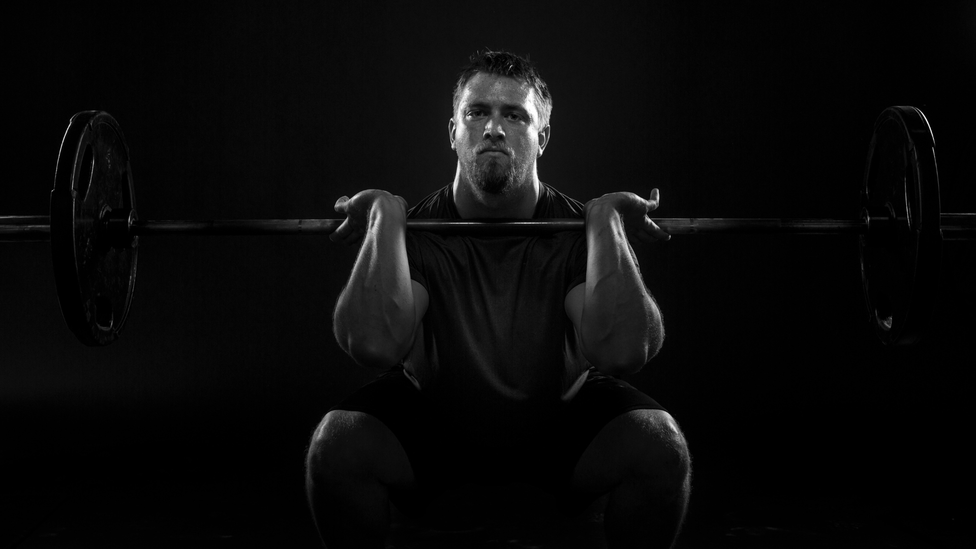 Male weightlifter executing a front squat with a barbell, showcasing proper technique and strength training.