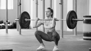  Female athlete deep in a front squat position, displaying optimal depth, bar placement, and quad engagement.