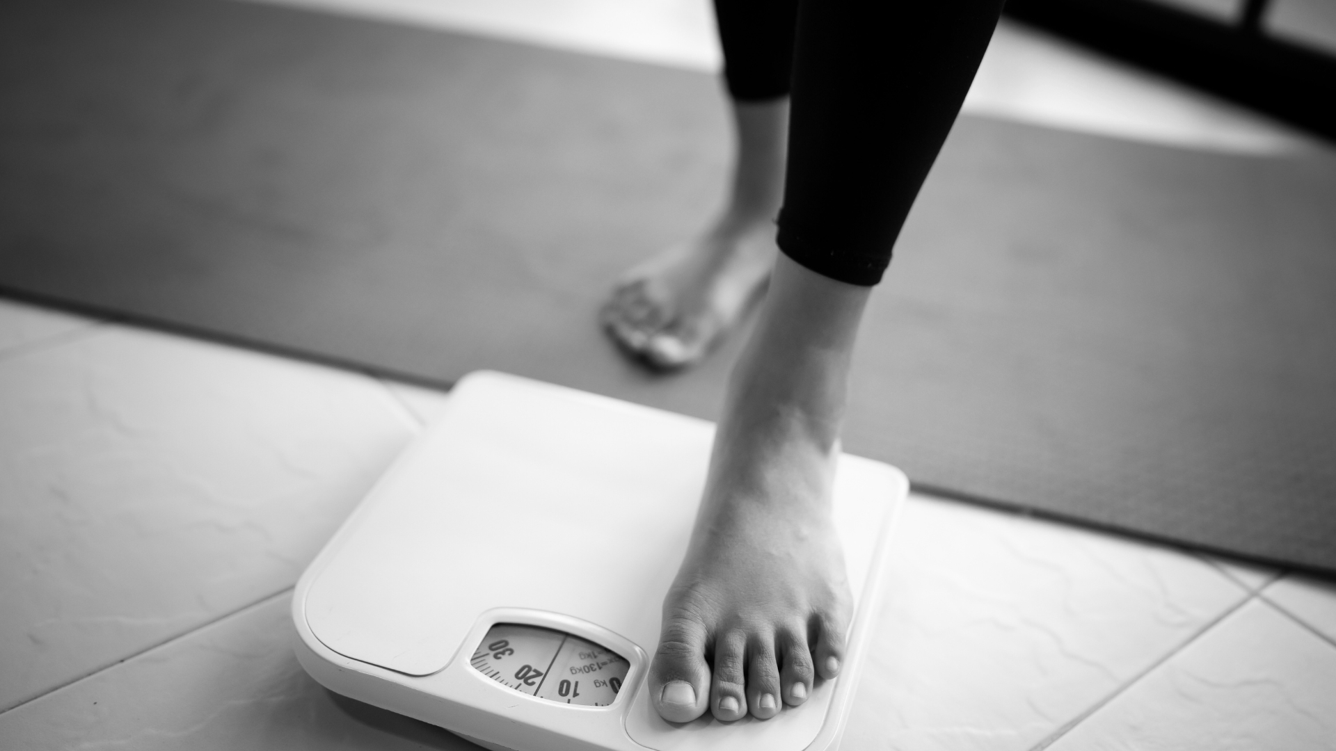 A close-up of a person's foot stepping onto a scale, symbolizing weight management and tracking progress.