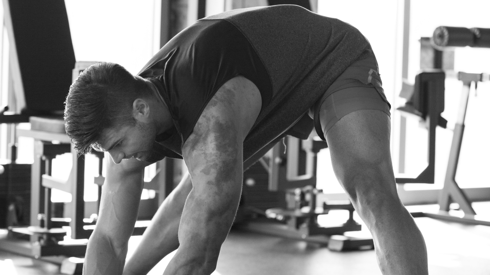  Athlete stretching hamstrings before a sprint workout in the gym.