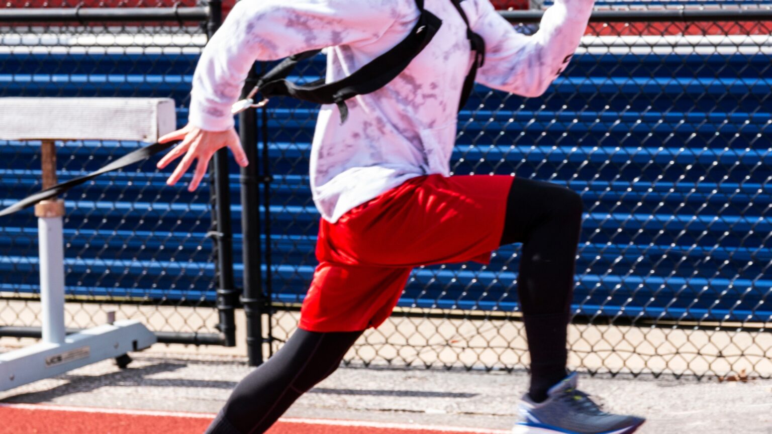 Athlete performing a resisted sprint using a harness on a track