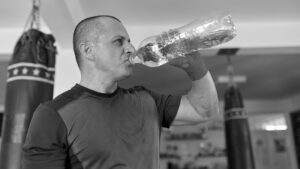 Hydration is key as this athlete drinks water in a fighting gym.