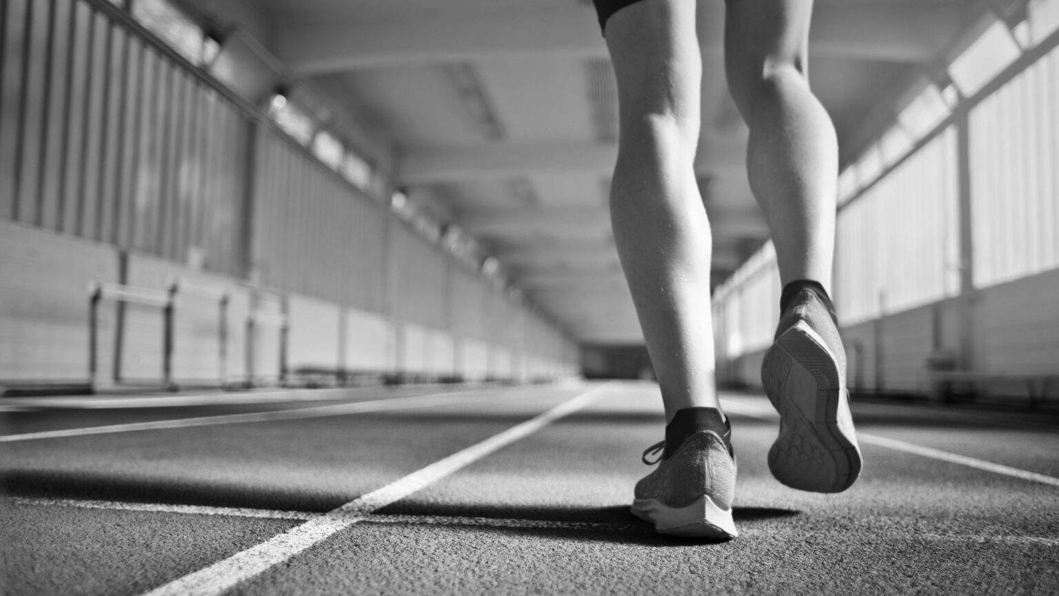 A close-up of a runner's feet on a track, demonstrating proper running mechanics for combat sports training.