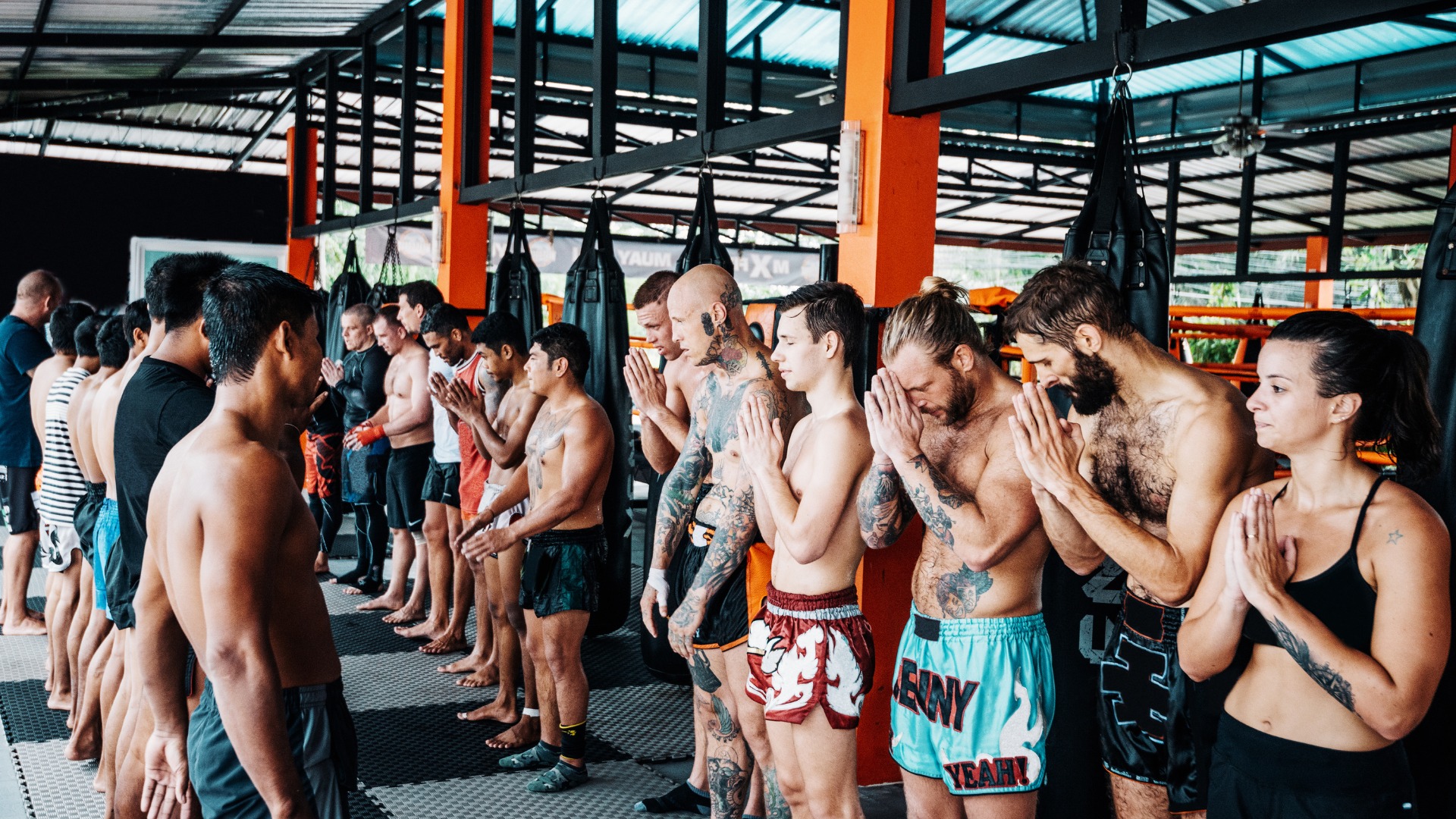 A group of Muay Thai trainees bowing in respect during a traditional class in Thailand.