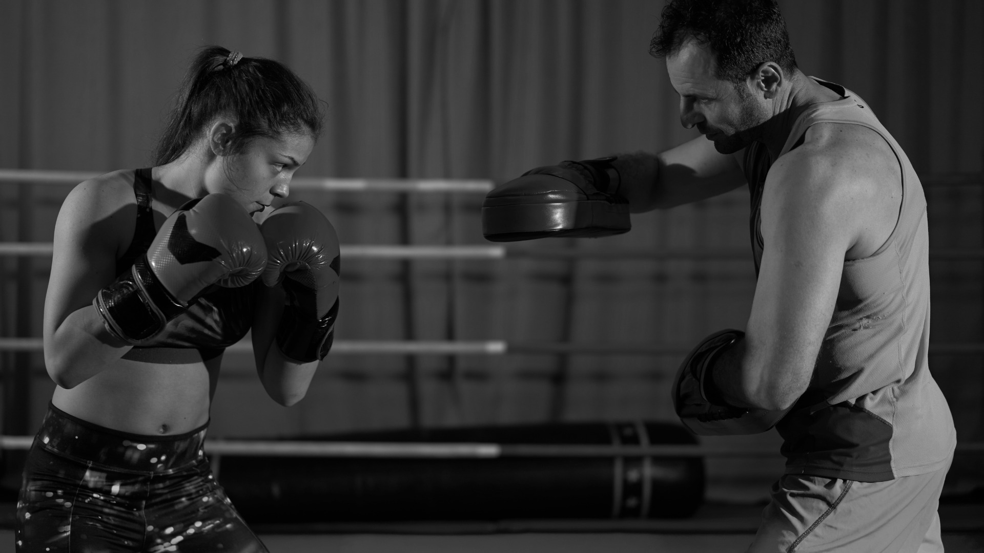 A female boxer training with a coach, practicing focus mitt drills in a boxing ring.