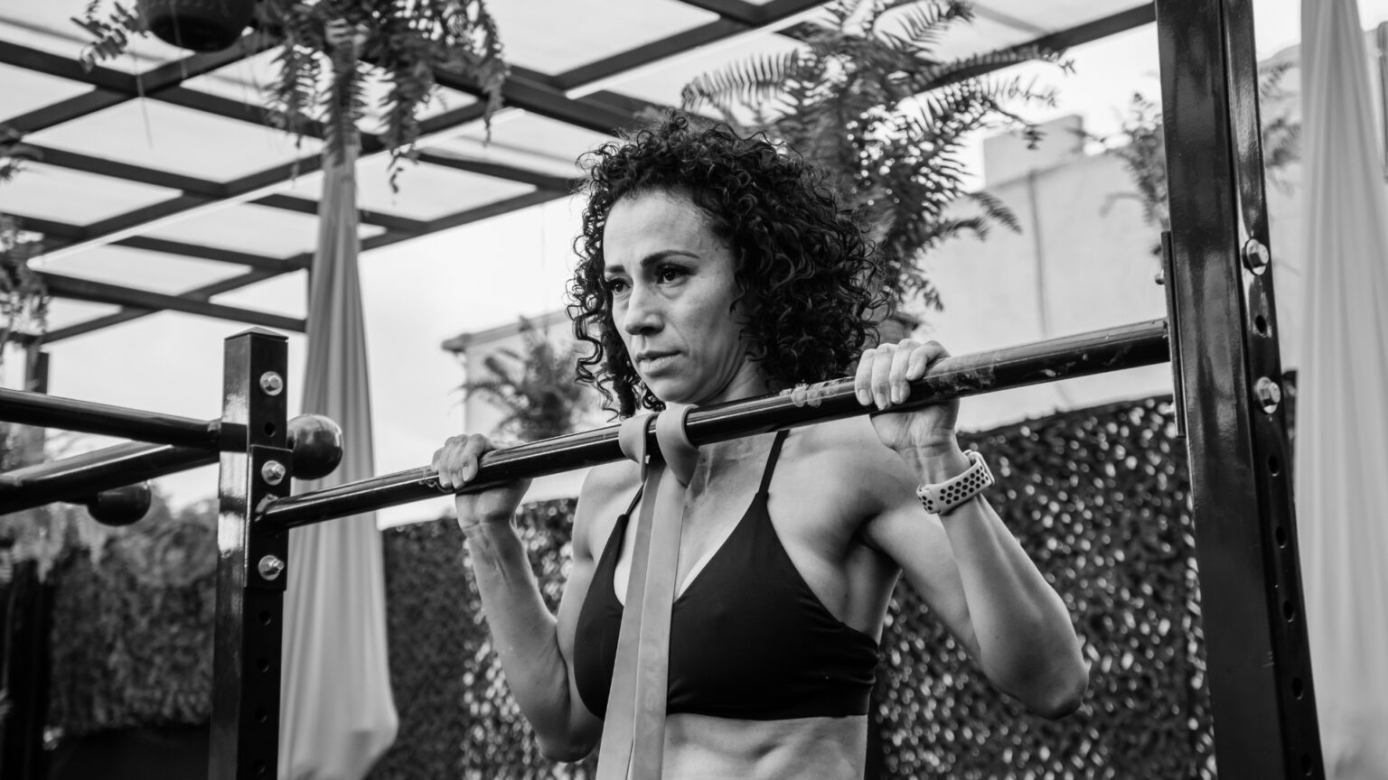 Woman performing a pull-up with a resistance band, focusing on scapular stability and shoulder strength.