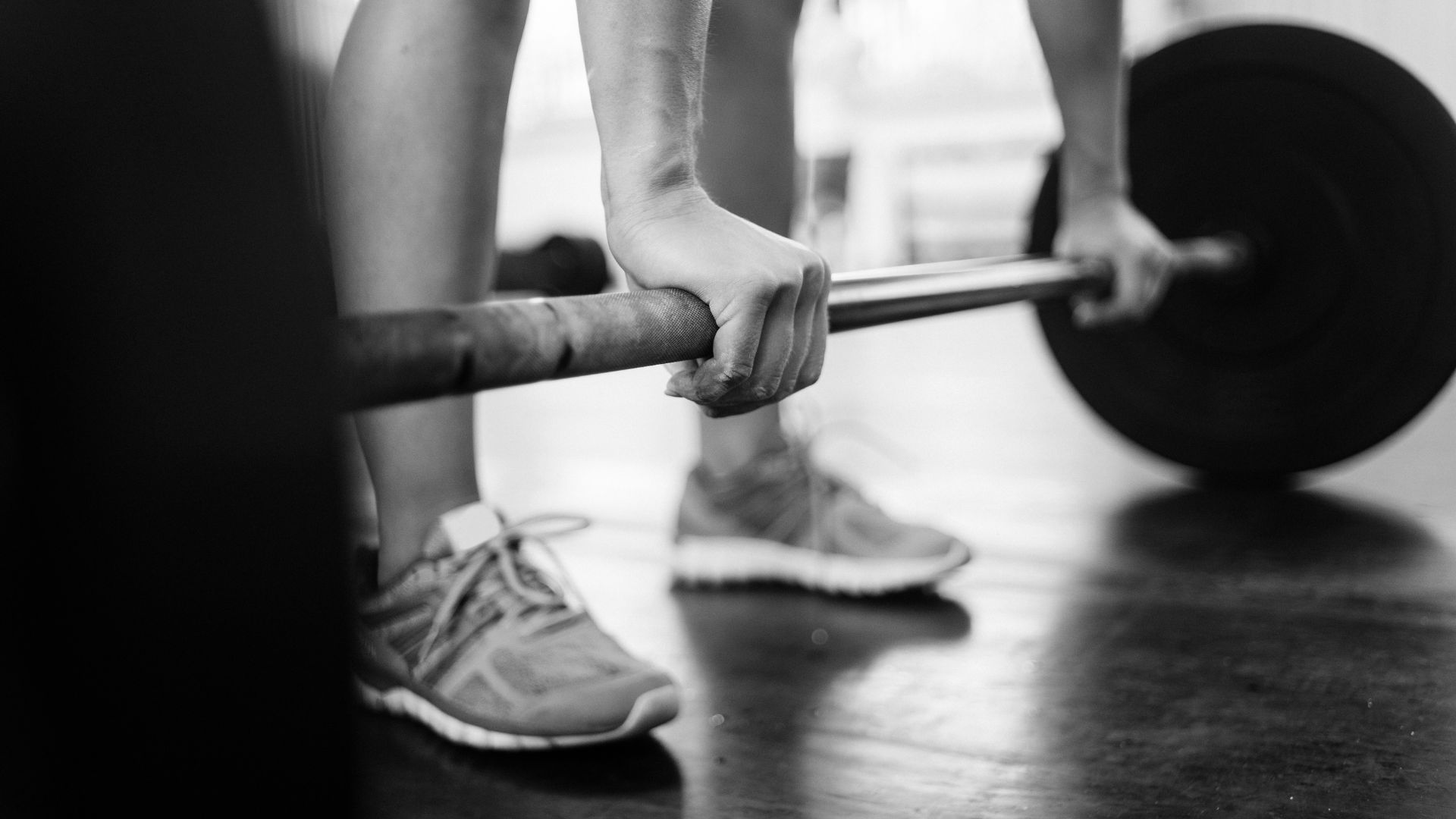 Close-up of hands gripping a barbell, highlighting strength training essentials.