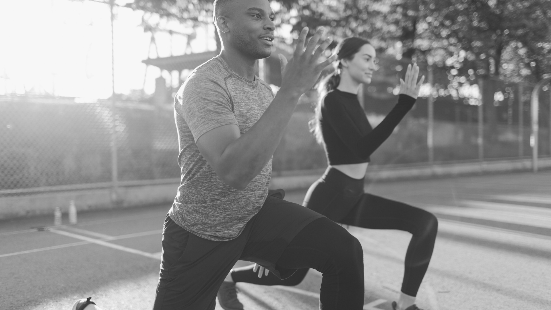 Two athletes performing lunges outdoors as part of strength and endurance training.