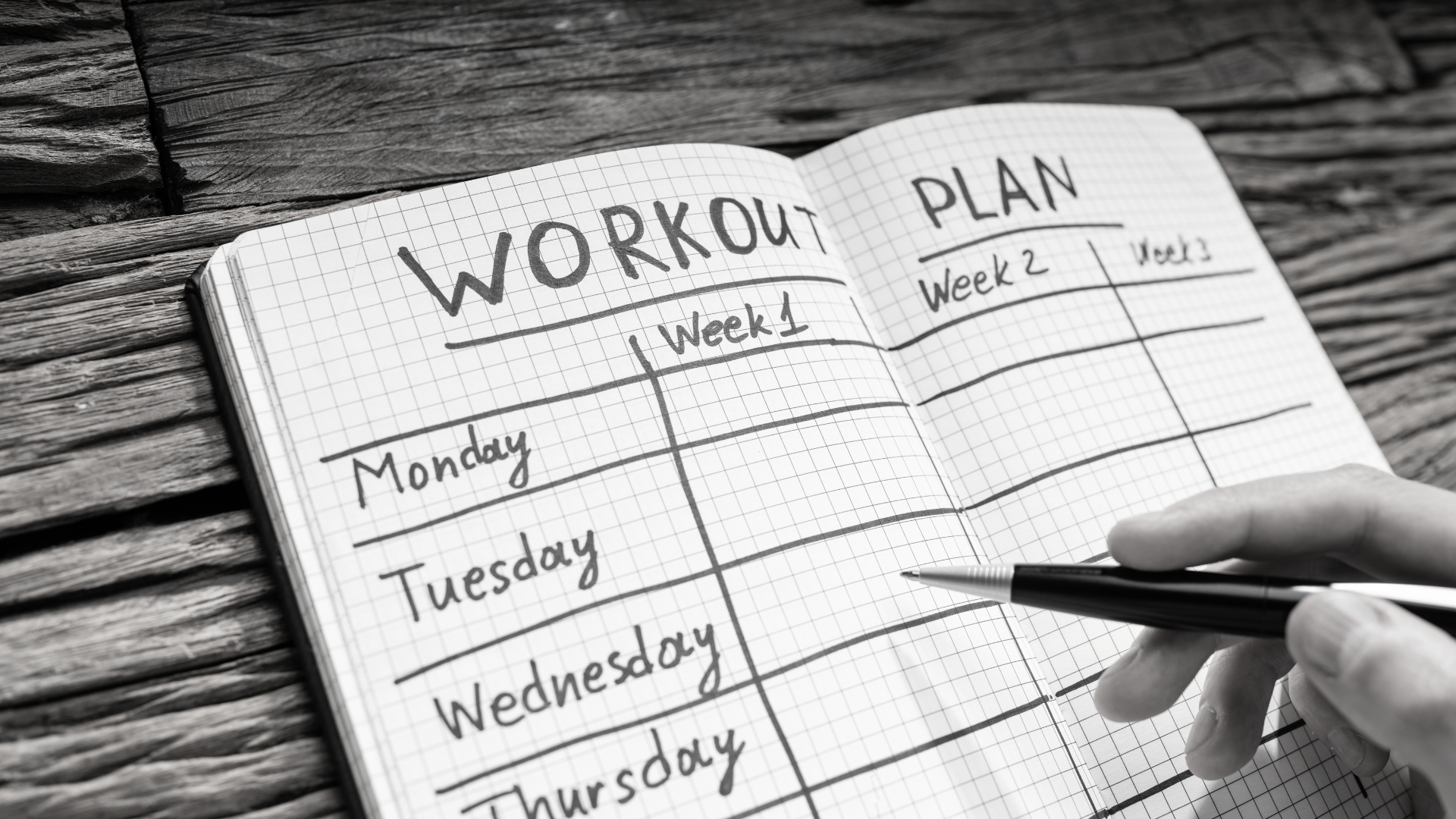 Workout training split written in a fitness journal, organizing weekly strength sessions.