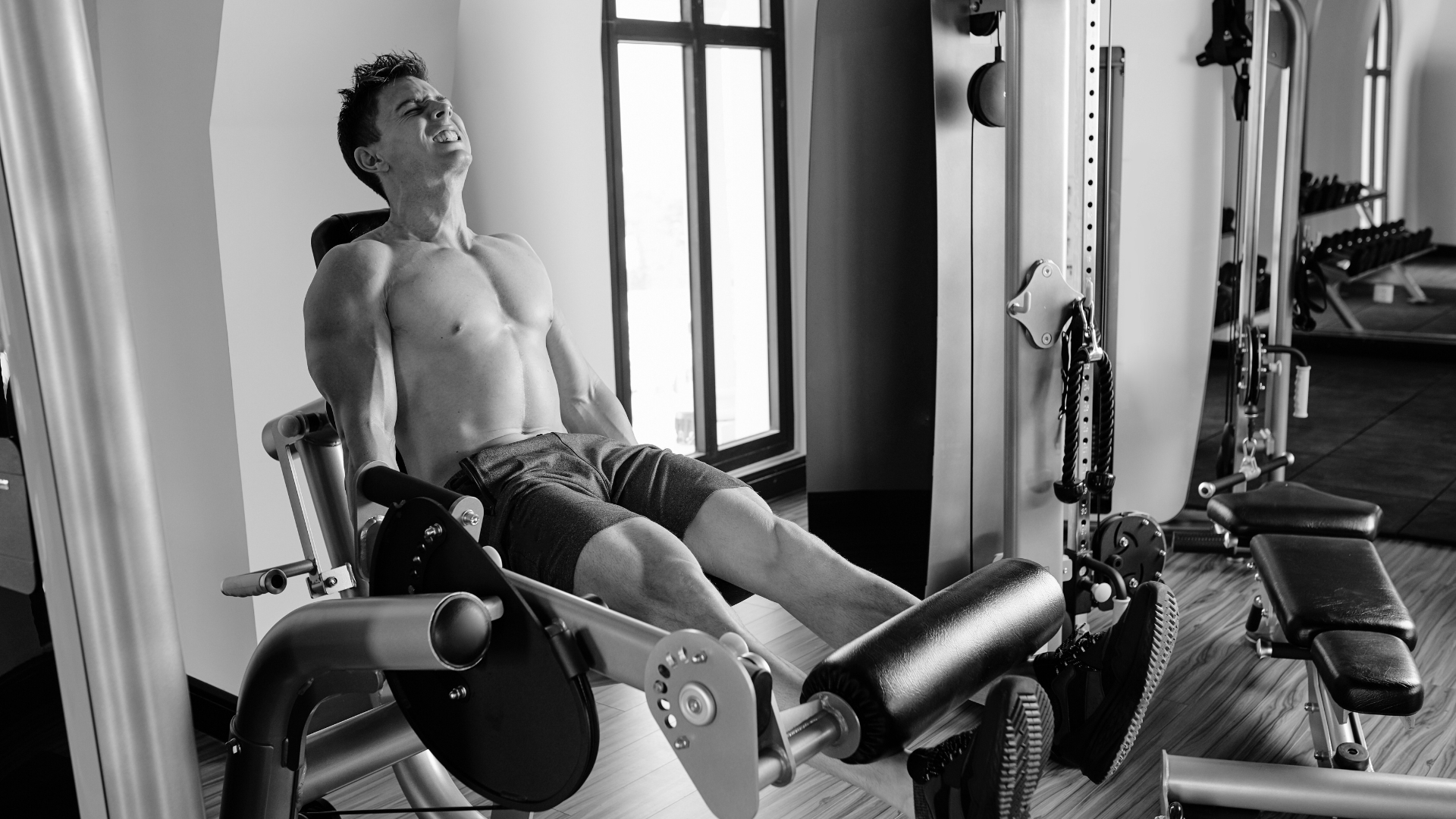 Male athlete performing intense leg extension during strength training workout.