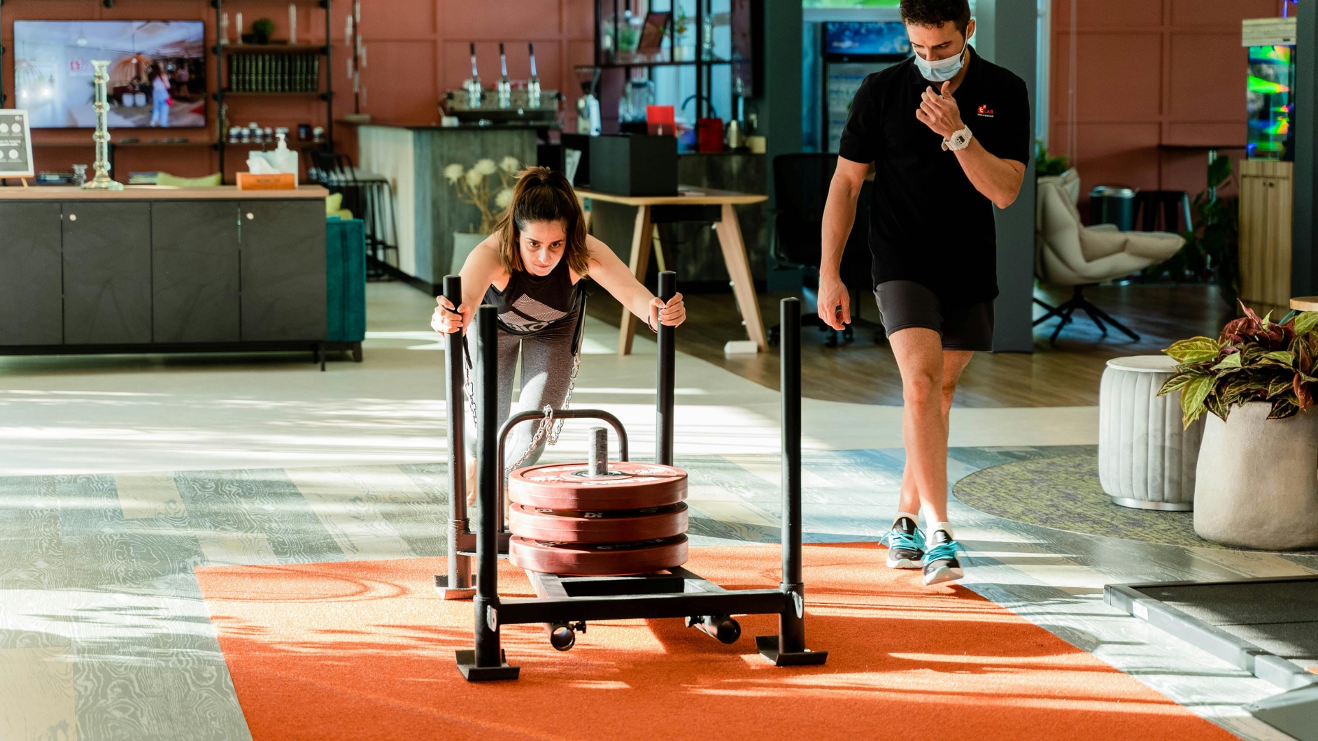 Female athlete pushing weighted sled in a strength and conditioning gym.