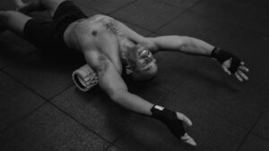 Athlete doing thoracic-spine foam-roller extension to prep posture before a workout for the back