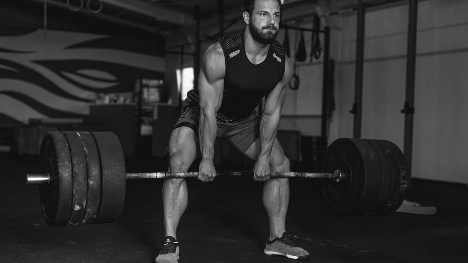 Male powerlifter driving from the floor with strong lat tension during heavy sumo deadlift