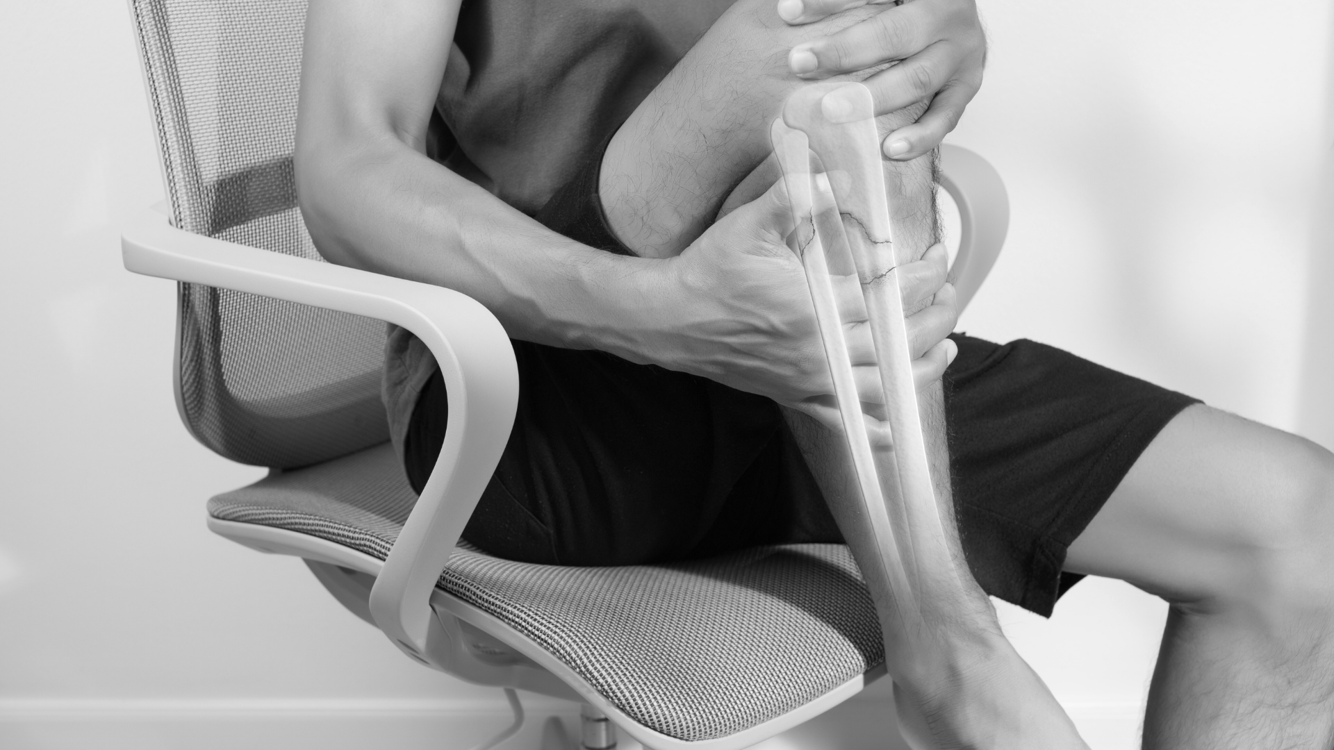 Man seated holding lower leg with tibia overlay highlighting medial tibial stress along the inner border (MTSS).